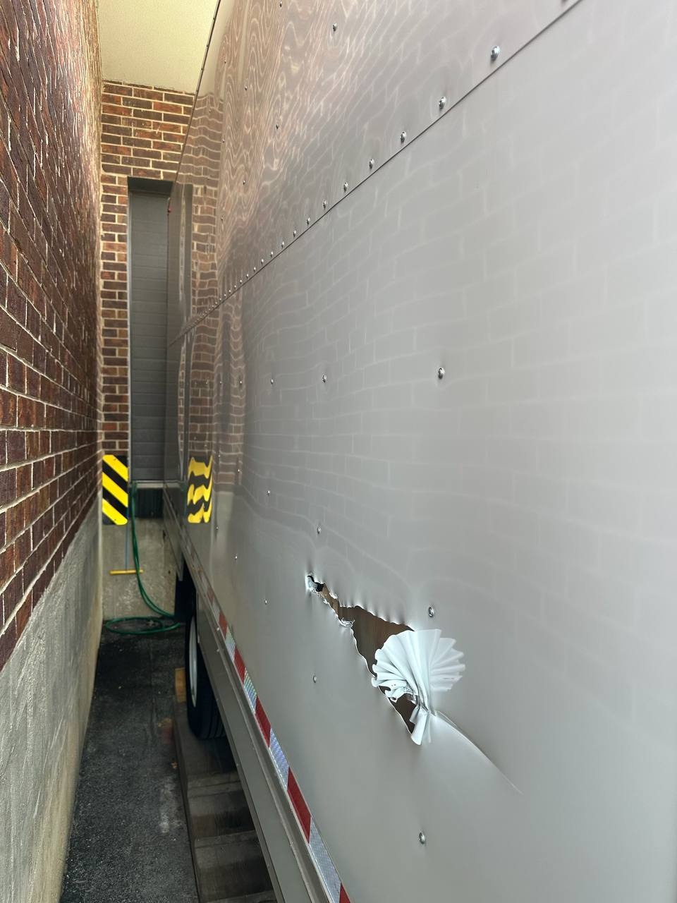 Damaged box truck body panel before repair